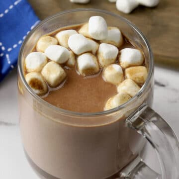 Glass mug of hot chocolate topped with mini marshmallows.