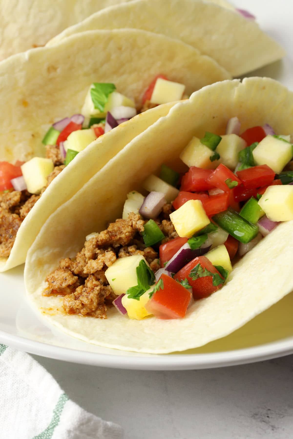 Spiced ground pork topped with pineapple pico de gallo in a tortilla.