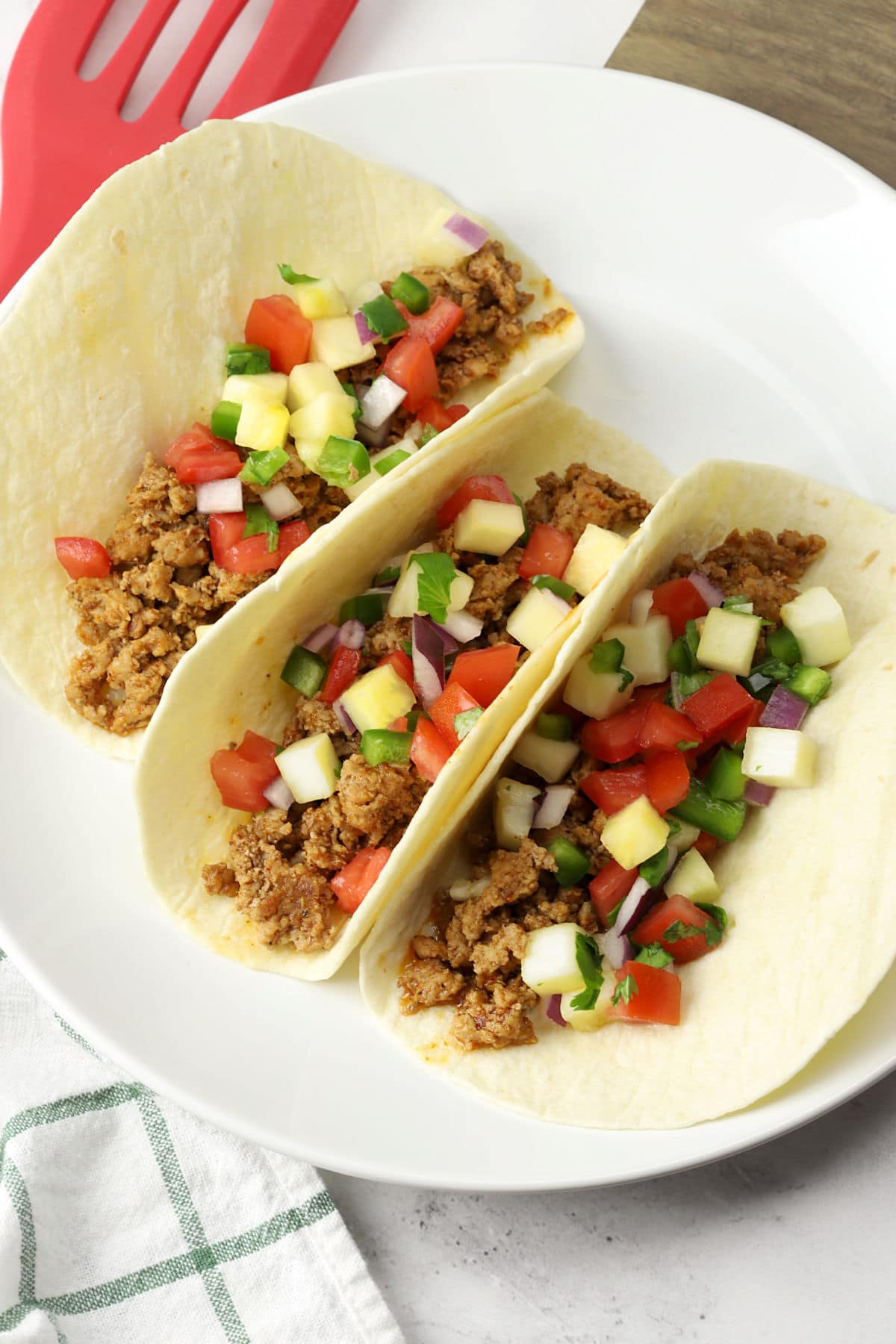 Three ground pork tacos on a white plate.