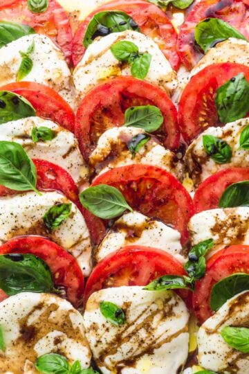 Mozzarella and tomato slices with basil leaves, drizzled in balsamic glaze.