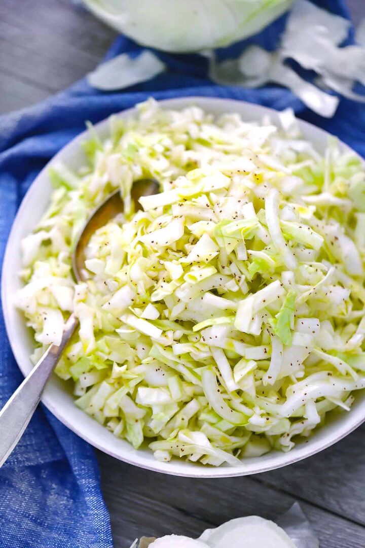 Coleslaw in a white bowl with a blue towel.