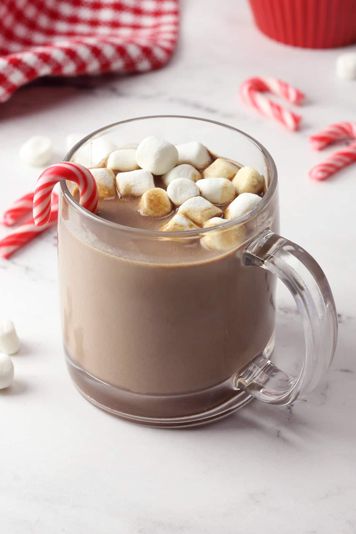 Glass mug filled with peppermint hot chocolate, topped with marshmallows.