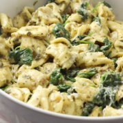 A bowl of creamy tortellini with spinach.