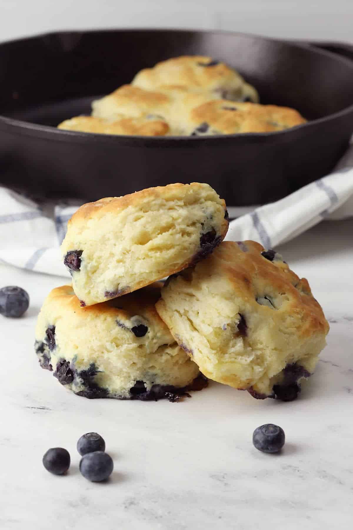 Three blueberry biscuits stacked on a counter top.