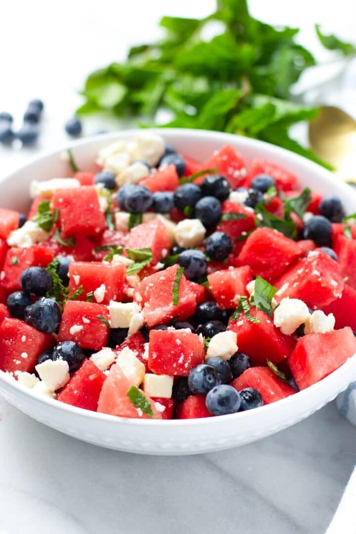 Cubed watermelon, blueberries, and feta in a white bowl.
