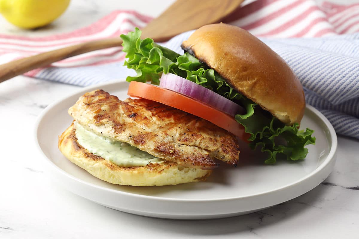 Lemon pepper chicken sandwich spread out on a white plate to show all ingredients.