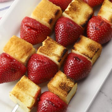 Grilled strawberry shortcake kebabs on a white serving plate.