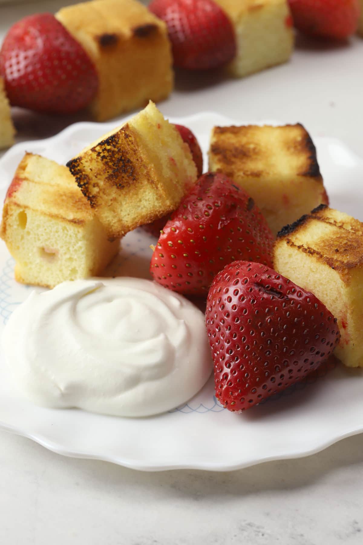 Grilled pound cake and strawberries on a serving plate with whipped cream.