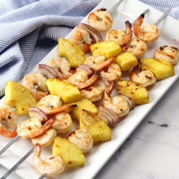 White serving plate filled with pineapple shrimp skewers.