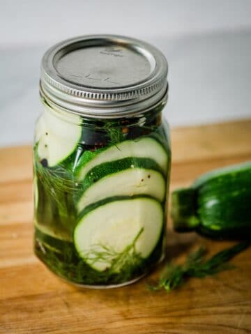 Glass jar filled with zucchini pickles.