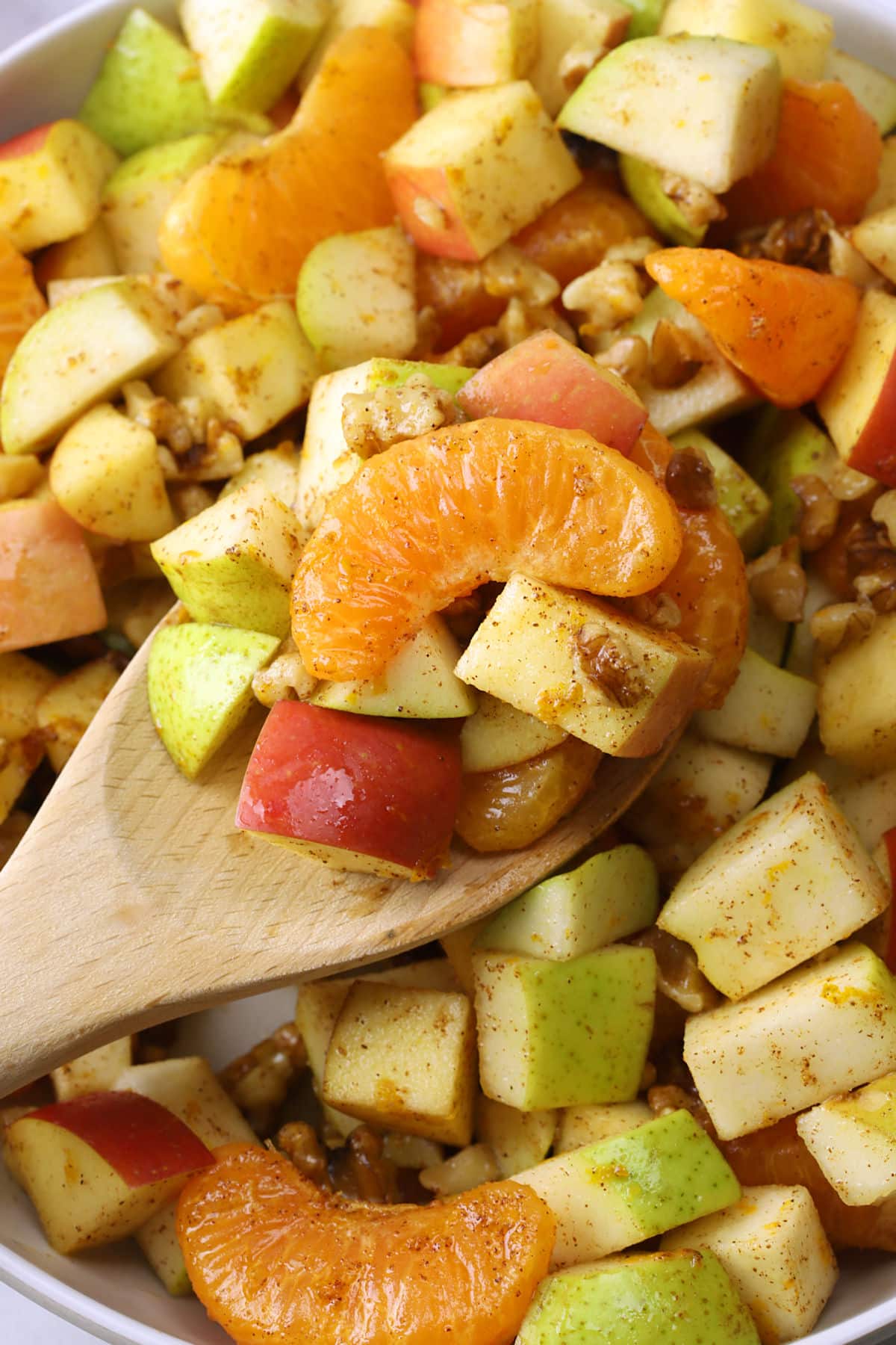 Wood spoon scooping winter fruit salad.