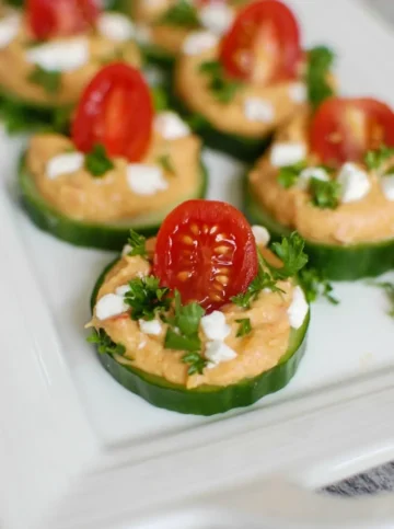 Cucumber slices topped with hummus and tomatoes.