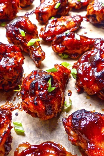 Baked barbecue wings with a green garnish.