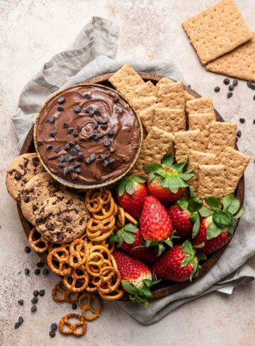 Brownie batter dip on a serving tray with cookies, pretzels, and graham crackers.