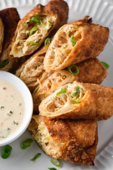 Chicken egg rolls sliced in half and served with a dipping sauce.