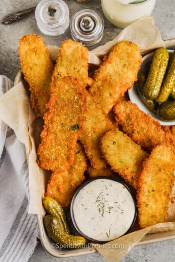 Crispy fried dill pickles in a serving tray with sauce.