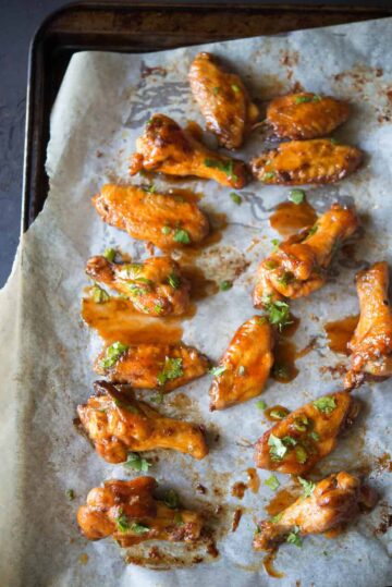 A sheet pan filled with baked chicken wings coated in sauce.