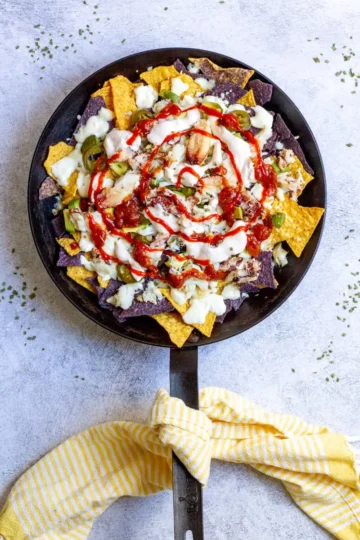 Pan filled with nachos topped with crab and sauce.