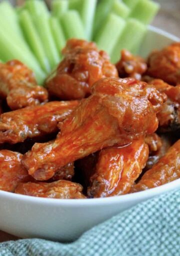 Buffalo wings in a bowl with celery sticks.