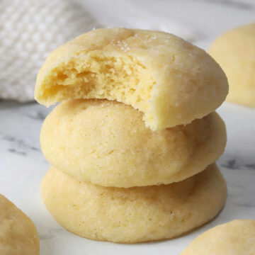 A stack of soft sugar cookies, one with a bite missing.