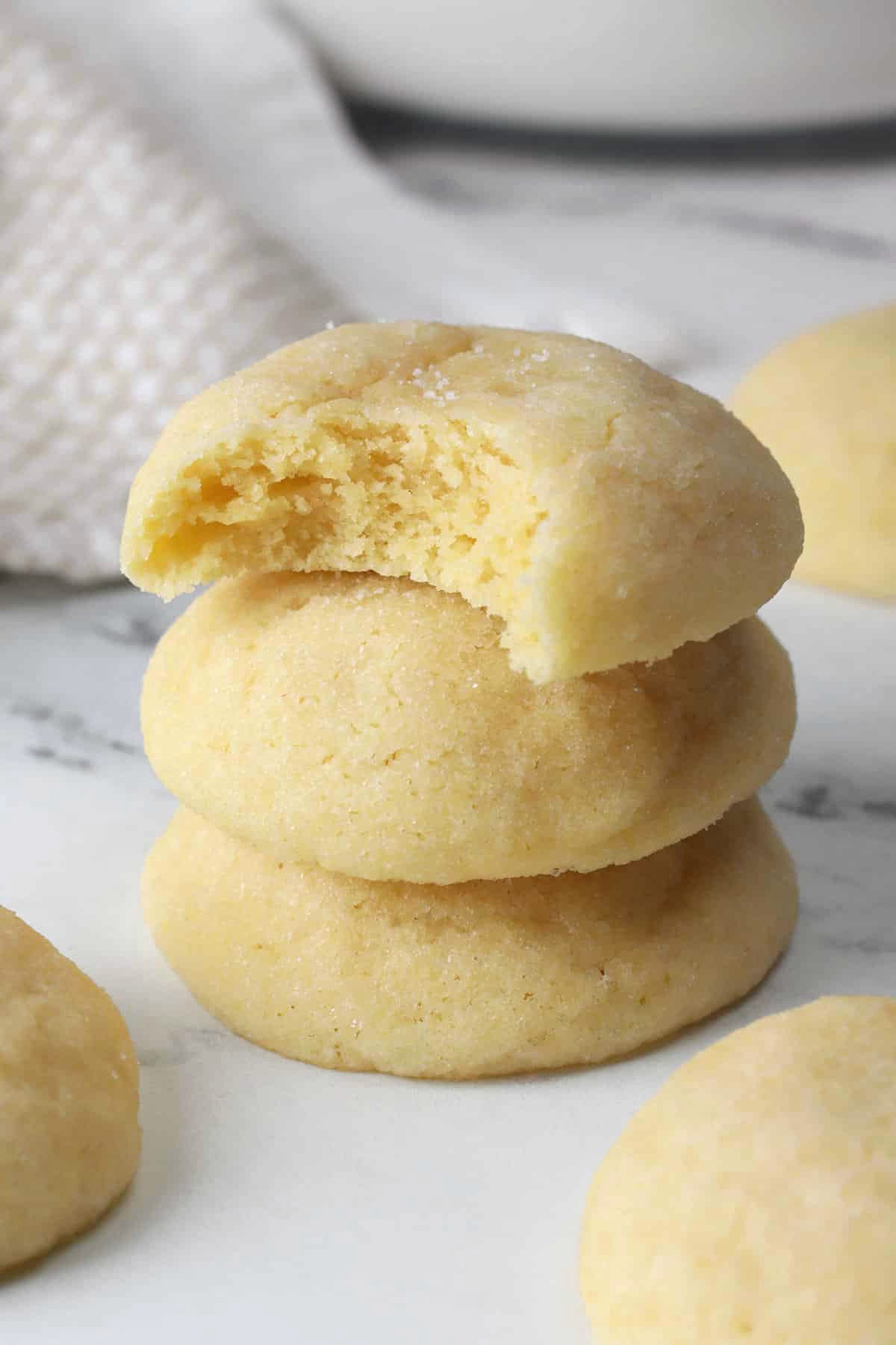 A stack of soft sugar cookies, one with a bite missing.