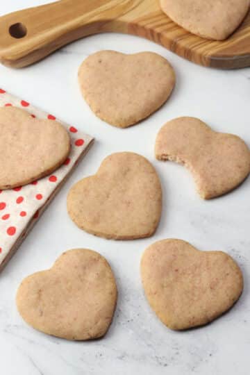 Heart shaped strawberry shortbread cookies on a countertop.
