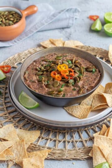 Black bean dip in a serving bowl with tortilla chips and sliced pepper garnish.