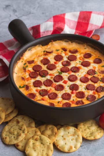 Cast iron pan filled with melted cheese and mini pepperonis on top.