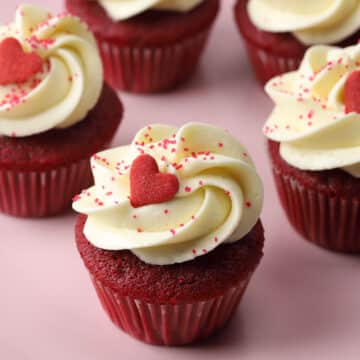 Close up of mini red velvet cupcake topped with a red heart shaped sprinkle.