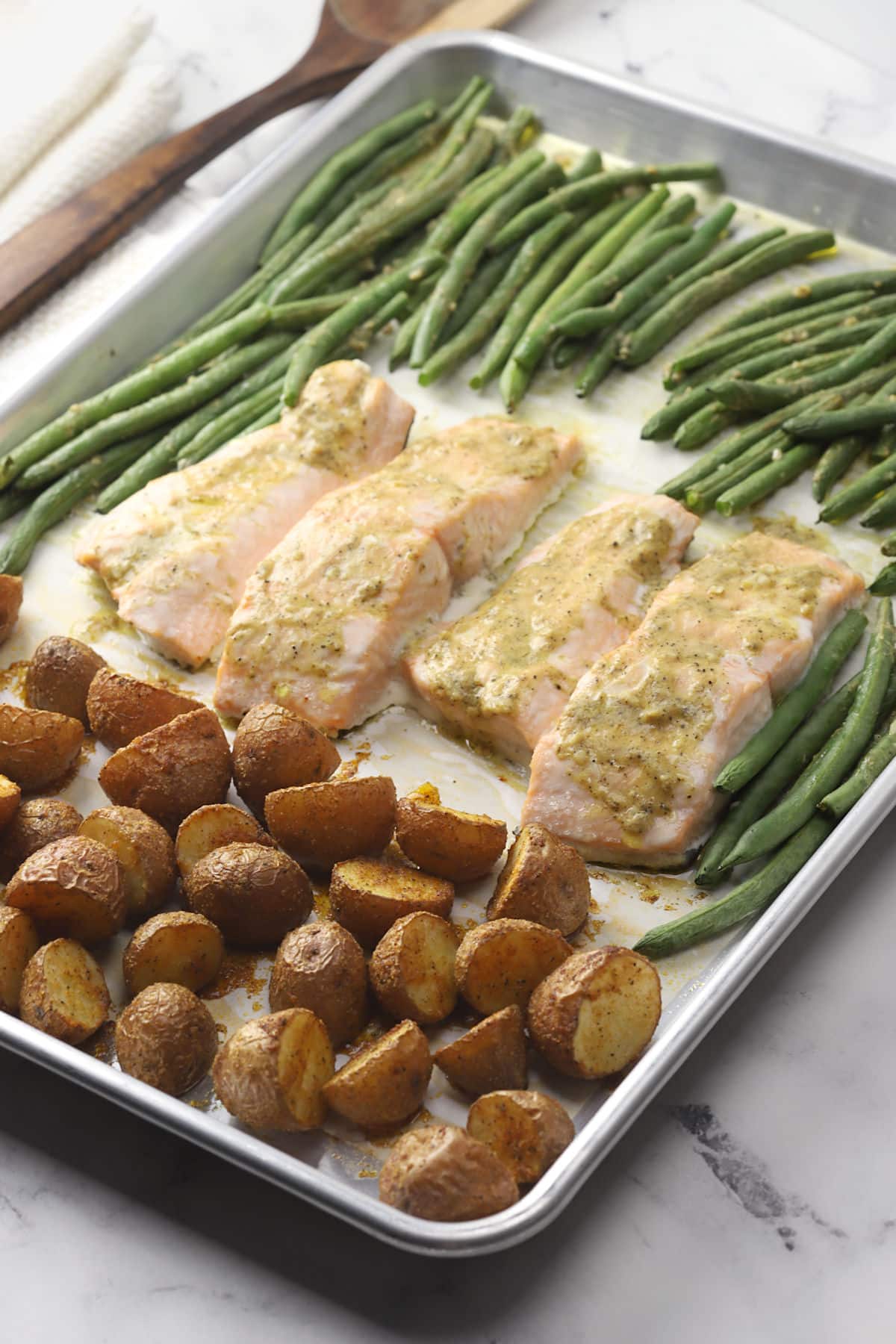 Baked salmon, green beans, and roasted potatoes on a sheet pan.
