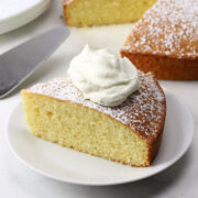 A slice of Irish tea cake topped with whipped cream on a plate.