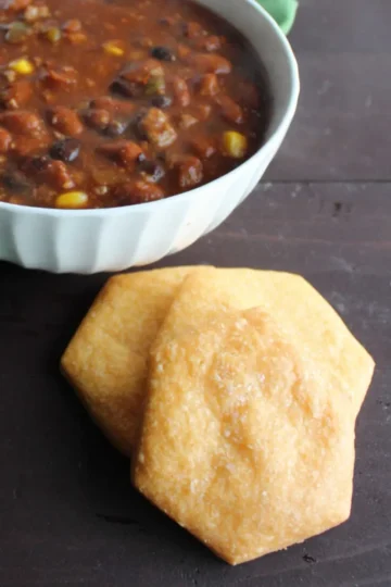 Three cheese crackers next to a bowl of chili.