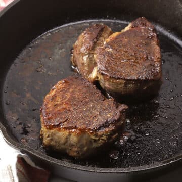 Close up of two filet mignon steaks in a cast iron pan.