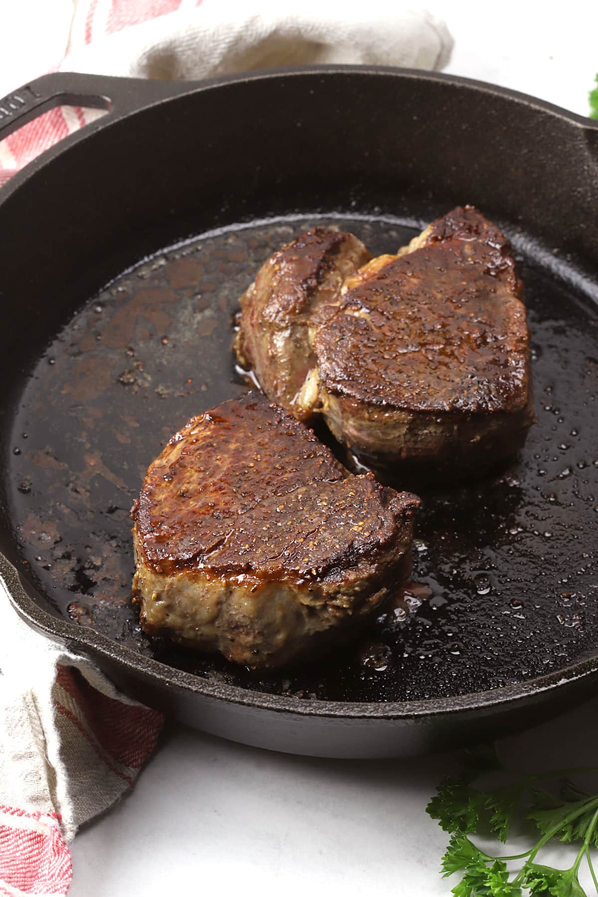 Close up of two filet mignon steaks in a cast iron pan.