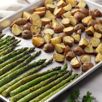 Roasted potatoes and asparagus on a metal sheet pan.