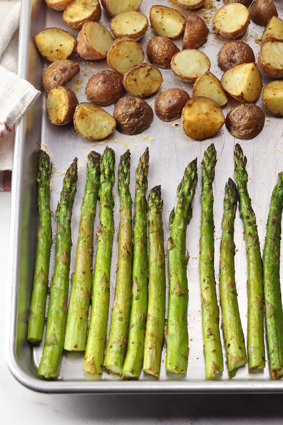 Close up of roasted asparagus and potatoes on a sheet pan.