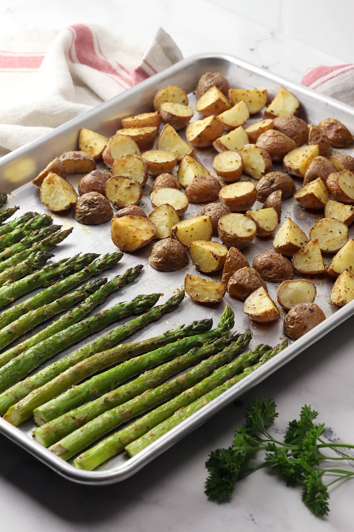 Roasted potatoes and asparagus on a metal sheet pan.