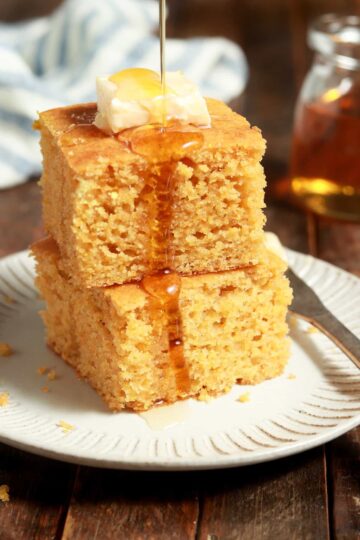 Two squares of cornbread on a plate with a fork.