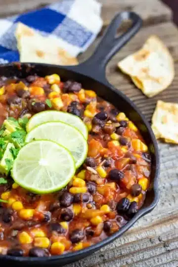 A cast iron skillet filled with bean chili and garnished with lime.