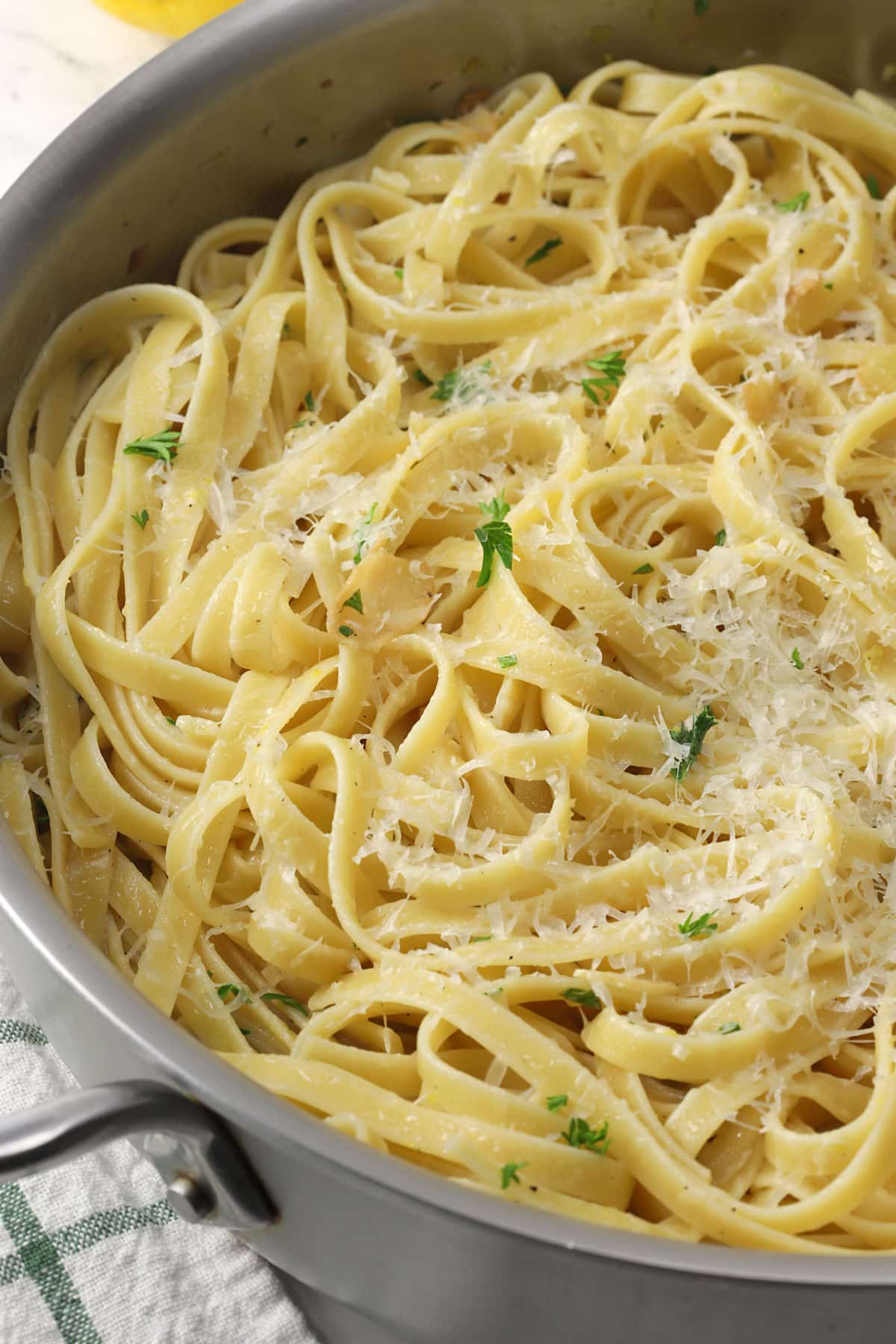 Close up of fettuccine noodles topped with parmesan in a pan.
