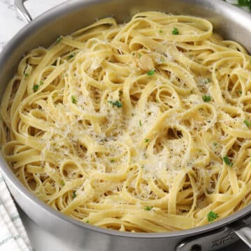 A saute pan filled with lemon garlic pasta topped with parmesan cheese.