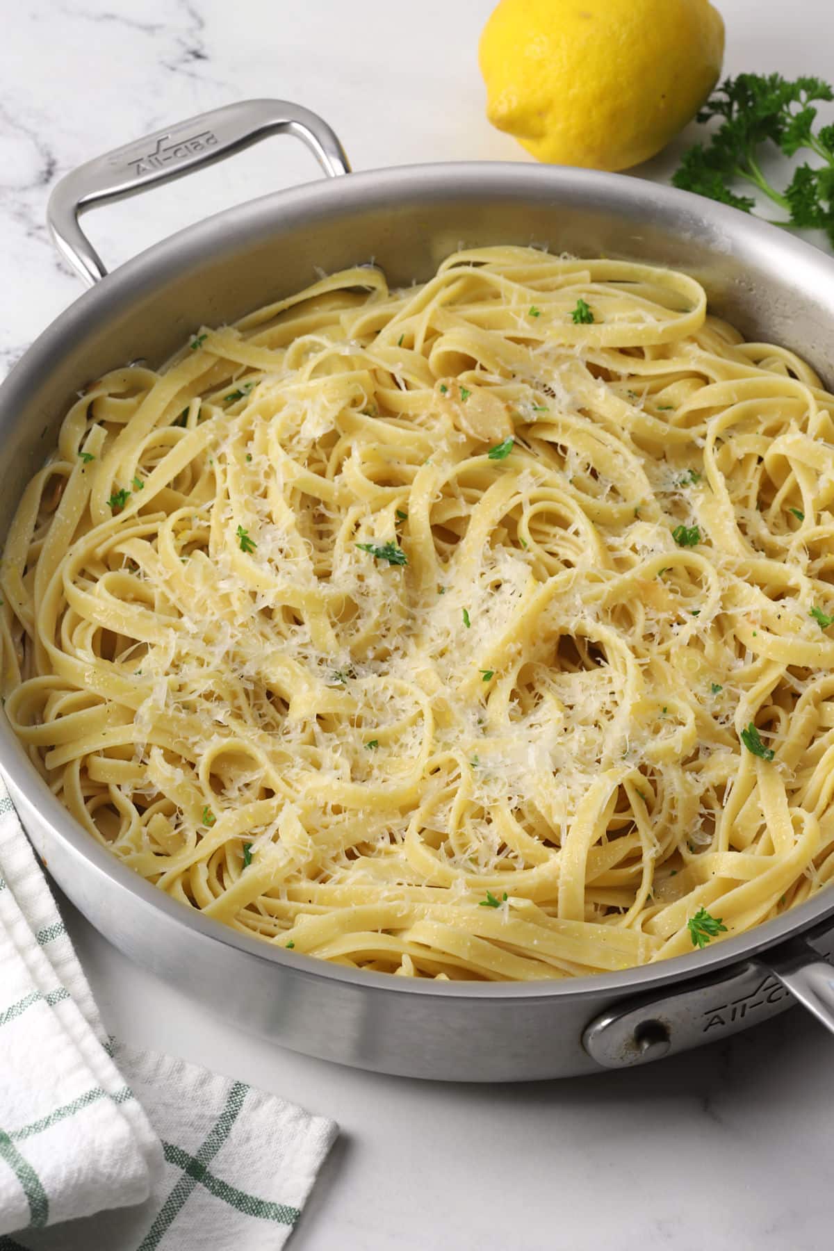 A saute pan filled with lemon garlic pasta topped with parmesan cheese.