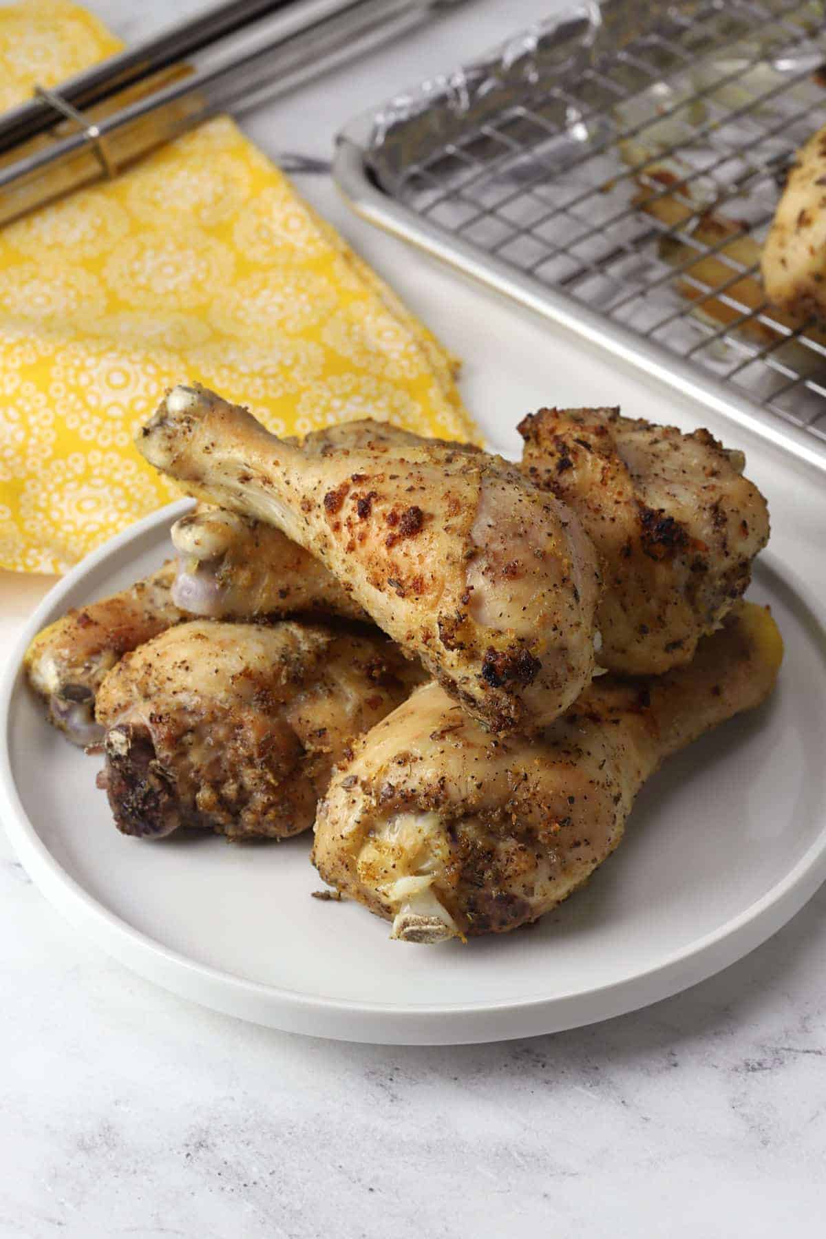 Lemon pepper drumsticks stacked on a white plate.