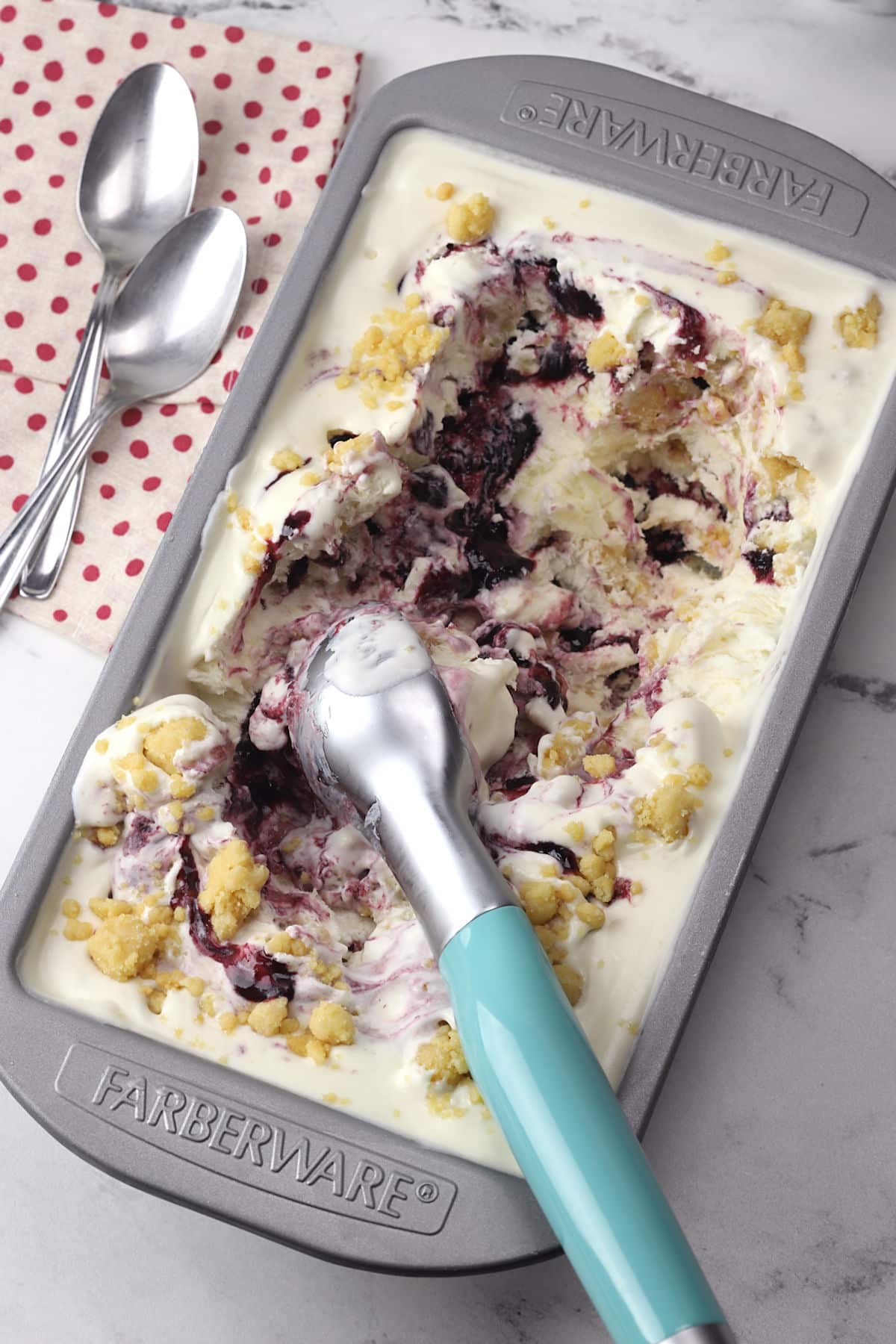 A metal loaf pan filled with boysenberry ice cream with streusel.