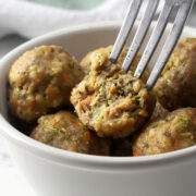 A fork piercing a turkey veggie meatball with a bite missing.