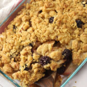 Close up of apple blackberry crumble scooped by a wooden serving spoon.