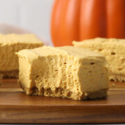 A pumpkin cheesecake square with a bite missing.