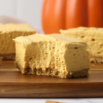 A pumpkin cheesecake square with a bite missing.