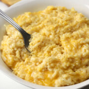A metal fork in a bowl of cheesy rice.