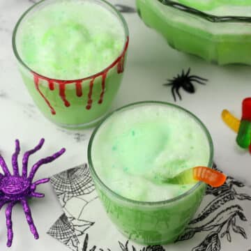 Two decorated glasses filled with green sherbet punch.